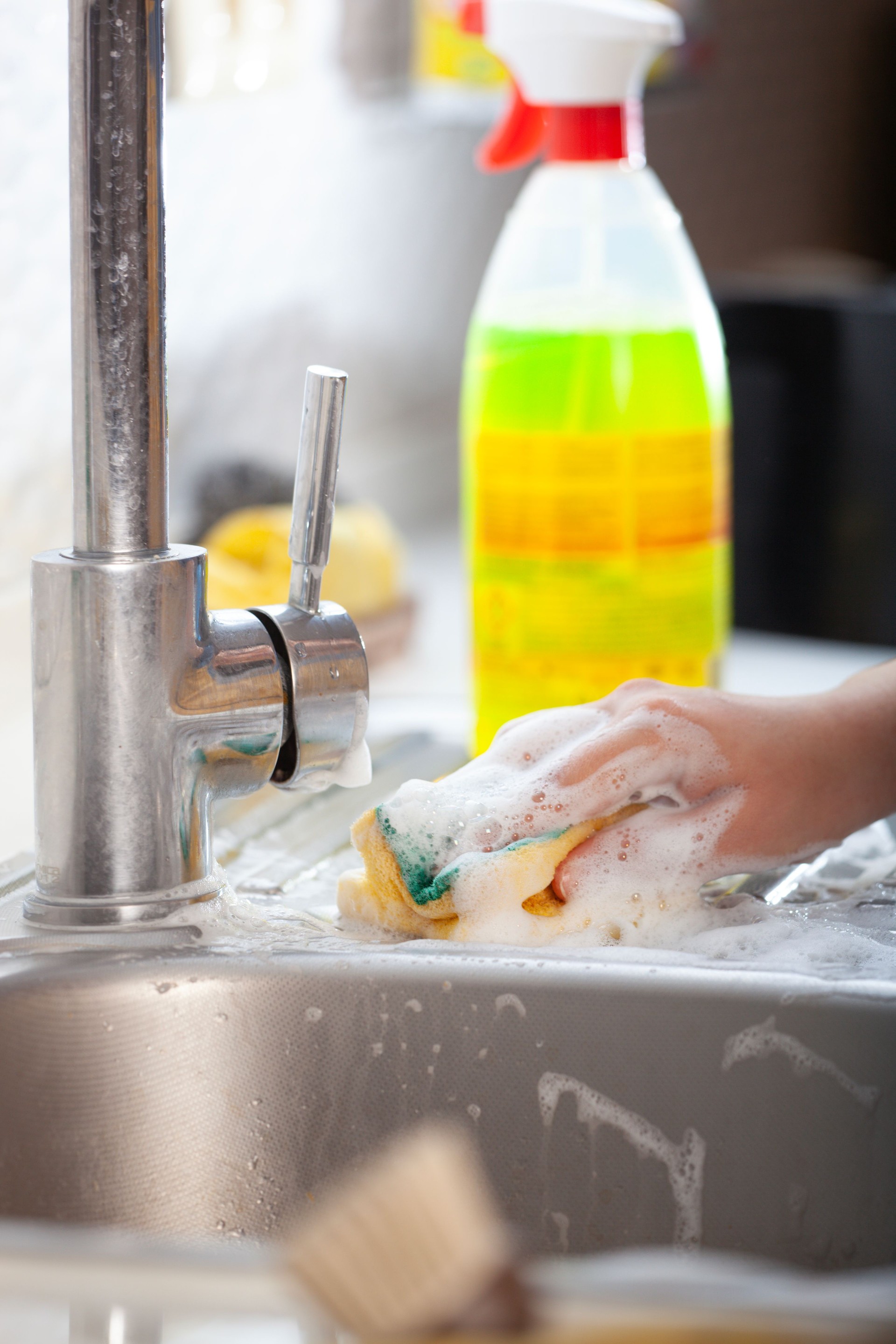 Cleaning the sink with a sponge and spray